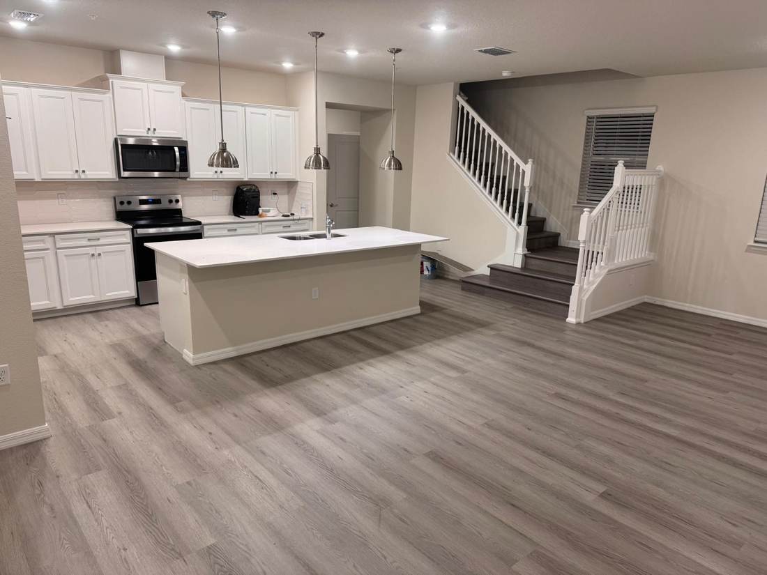 Open kitchen and living area with gray vinyl plank floor and new stair treads